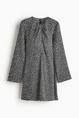 Vestido corto de escote redondo con detalle girado y abertura frontal. Presenta mangas largas amplias con aberturas en los puños, costura decorativa curva sobre la cadera y falda con leve vuelo. Incluye cierre oculto en la espalda.