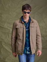 Campera de gabardina color tostado, con cuello camisero, cierre frontal con botones metálicos y bolsillos frontales con solapa.