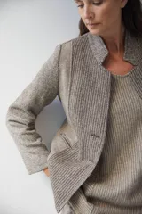 Chaqueta corta color marrón con cuello solapa y diseño con patchwork de telas. Manga larga con detalle de coderas aplicadas. Cierre frontal mediante botones y bolsillos ojal. Con forro.