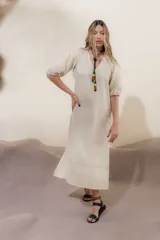 Vestido largo azul oscuro de lino 100% con escote en V, mangas abullonadas con elástico en el puño y pespunte en contraste. Presenta detalle de punto smock en el canesú y bolsillos laterales.