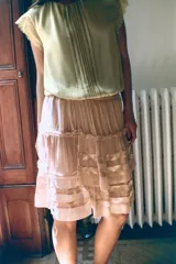 Falda corta de tiro bajo confeccionada en viscosa, con diseño de volantes superpuestos y frunces. Presenta detalle de lazadas laterales ajustables y cierre lateral con cremallera oculta.