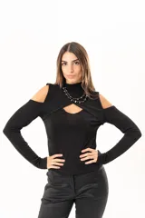Polera negra de manga larga con diseño de hombros descubiertos y cuello alto. Presenta un recorte frontal en el pecho que crea un efecto de superposición.