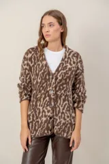 Cárdigan de punto con textura suave y estampado animal print en tonos marrones y beige. Presenta escote en V, cierre frontal con botones y mangas largas holgadas.