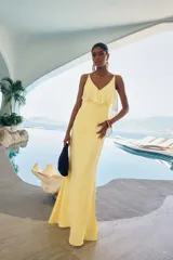 Vestido largo color amarillo de corte sirena, con escote en V, tirantes finos y detalle de volados en el pecho.