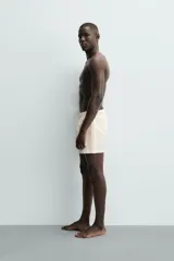 Short de baño de color beige con textura seersucker, cintura elástica con cordón ajustable, bolsillos laterales y forro interior.