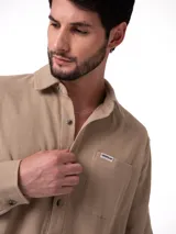 Camisa de manga larga Caterpillar confeccionada en tejido waffle de algodón color beige. Presenta cuello camisero, cierre frontal con botones perlados, puños abotonados y un bolsillo en el pecho con etiqueta de la marca.