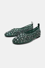 Zapato tipo bailarina color verde con apliques de strass plateados, confeccionado en mesh. Tiene tirador trasero y terminación en punta redonda. La suela mide 1 cm.