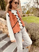 Chaleco color crema con ribete amarillo, de corte recto y sin mangas.