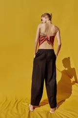 Pantalón de lino marrón oscuro, de corte barrel con pernera holgada que se estrecha hacia el tobillo, cintura elástica y bolsillos delanteros.