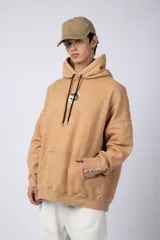 Buzo canguro oversize de algodón friza con efecto de teñido artesanal acid wash en color gris oscuro. Presenta capucha con cordones ajustables, bolsillo frontal tipo canguro y estampa pequeña en el pecho.