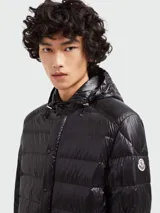 Campera puffer corta con capucha Moncler Gliere, color negro, con cierre frontal de botones a presión y bolsillos laterales con cierre. Diseño acolchado horizontal.