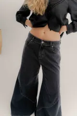 Pantalón de jean color beige, de tiro medio, corte amplio y ruedo acampanado.