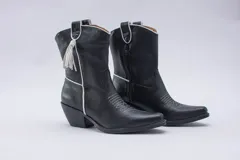 Botas estilo texanas de caña media, confeccionadas en cuero con estampado animal print tipo vaca en blanco y negro. Presentan un diseño de punta fina y taco cuadrado.