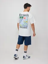 Remera oversize color verde claro, de manga corta, con estampa en el pecho y etiqueta cosida en el borde inferior.