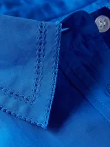 Vestido camisero de corte oversize confeccionado en algodón orgánico. Presenta cuello inglés, cierre frontal de botones, mangas largas con puños abotonados y largo hasta la rodilla. Incluye el logo de la marca bordado en uno de los puños.