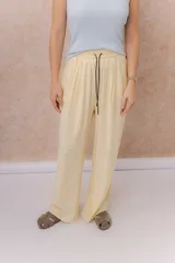 Pantalón amarillo de corte amplio y pierna recta, confeccionado en tela liviana con caída fluida. Cuenta con cintura elastizada, cordón regulable en contraste y bolsillos laterales.