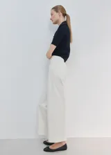 Jeans estilo wide leg de tiro alto en color crudo, con diseño de pernera ancha, trabillas para cinturón y costuras frontales marcadas.
