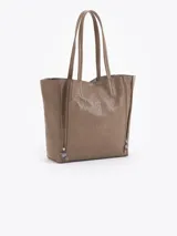 Cartera tipo shopper de cuero vacuno flor graneado, con formato amplio y estructura flexible. Presenta dos cierres verticales decorativos en el frente con tiracierres personalizados y doble manija de hombro.