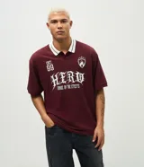 Remera de corte boxy confeccionada en piqué de algodón color bordó. Presenta cuello polo en color blanco con detalles en contraste, mangas cortas y estampa frontal con diseño gráfico y lettering en color blanco.