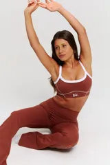 Conjunto deportivo de dos piezas color chocolate con detalles de costuras blancas. Incluye un top de tirantes finos con escote redondo y un pantalón largo de corte ajustado con aberturas en el bajo.
