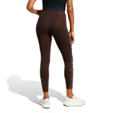 Calza deportiva Adidas de tiro alto, color marrón, con diseño ajustado y bandas laterales con estampado animal print. Presenta el logo de la marca bordado en la parte superior.