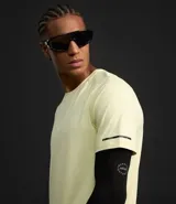 Remera deportiva de hombre con tecnología dry fit, cuello redondo y manga corta. Presenta un diseño liso en color beige con una pequeña etiqueta decorativa en el dobladillo.