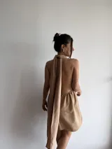 Vestido corto color beige, con escote halter y espalda descubierta. Presenta cintura elastizada y falda con vuelo.