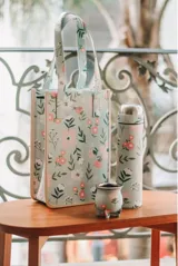 Bolso tipo matera con estampado multicolor, interior forrado en lona impermeable y bolsillo con cierre.