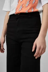 Pantalón de jean negro, de corte ancho y tiro alto, con ruedo deshilachado.