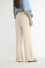 Pantalón tejido de corte recto y tiro alto, color beige, con cintura elástica ajustable mediante cordón y costura central vertical en cada pierna.