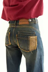 Pantalón de jean recto color gris oscuro, con efecto desgastado, recortes 360 y ajuste en cintura con presillas. Tiene tiro medio y detalles de bolsillos traseros con parches deshilachados.