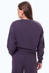 Buzo de felpa color negro con cuello redondo y ajuste holgado. Presenta un pequeño parche cuadrado con estampado a cuadros en el centro del pecho.