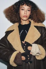 Guantes tipo mitones confeccionados en piel de ante, con diseño de dedos descubiertos, detalle de perforaciones circulares y cierre ajustable mediante lazada en el dorso.