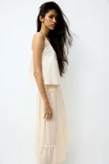 Pollera maxi de gasa color beige con efecto arrugado, con sección de punto smock en la cintura y diseño de volados escalonados en la parte inferior.