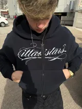 Campera con capucha y cierre frontal, color negro, con diseño gráfico estampado en el pecho y bolsillos tipo canguro.