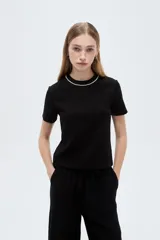 Remera negra de viscosa con cuello redondo decorado con una línea de strass, de mangas cortas y corte ajustado.