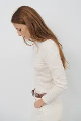 Polera de manga larga con cuello alto y detalle de volados en el borde. Confeccionada en tejido acanalado de textura suave y ajuste al cuerpo.