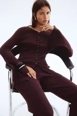 Cárdigan largo de punto acanalado color marrón oscuro, con escote en V y cierre frontal de botones de cúpula. Presenta remates acanalados de raya fina.