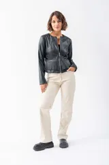 Chaqueta negra de eco cuero con corte ajustado, cierre frontal con cremallera y bolsillos laterales.