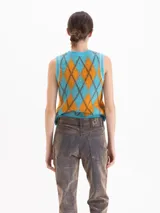 Chaleco de punto sin mangas con cuello redondo, confeccionado en hilado de baby alpaca. Presenta un diseño de rombos en colores celeste y naranja con bordes en tono oscuro.