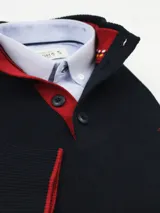 Buzo azul marino de algodón con cuello doble abotonado y ribete rojo en cuello, puños y ruedo.