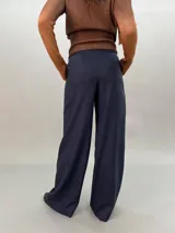 Pantalón de lana azul con estampado abstracto en tonos plateados. Tiro alto, corte amplio y bolsillos laterales ocultos.