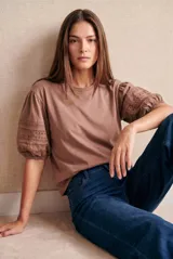 Remera de algodón color marrón con mangas abullonadas de largo 3/4, confeccionadas con detalle de encaje bordado y calado.