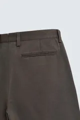 Pantalón de corte relaxed fit confeccionado en tejido de mezcla de algodón y lino. Presenta cintura con pliegues frontales, bolsillos laterales y bolsillos traseros de doble vivo. Cierre frontal con cremallera y botón.
