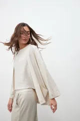 Kimono de corte holgado y diseño abierto, confeccionado en tejido con acabado laminado plateado. Presenta mangas anchas y bolsillos laterales aplicados.