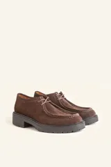 Zapato tipo wallabee de gamuza azul con costuras blancas a la vista y suela de goma negra con plataforma.