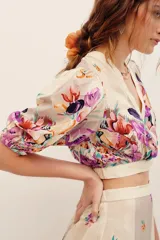 Top corto cruzado de viscosa con escote en V, mangas cortas abullonadas y diseño estampado con flores multicolores sobre fondo beige.