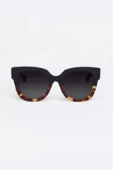 Lentes de sol Tiwi modelo Kerr, con montura gruesa de acetato color negro en la parte superior y estampado carey en la parte inferior.