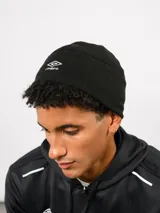 Gorro tipo beanie de Umbro, confeccionado en tejido polar negro, con el logo de la marca bordado en blanco en la parte frontal.