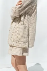 Blazer color crudo con diseño troquelado, cuello solapa, manga larga y bolsillos delanteros de plastrón.